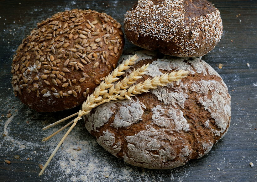 Three round seeded sourdough loaves resting on a floured steel bench.