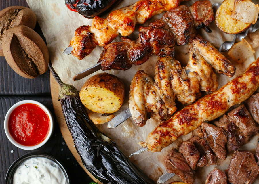 Grilled skewers, whipped dips and charred flatbread laid across paper down a long table.