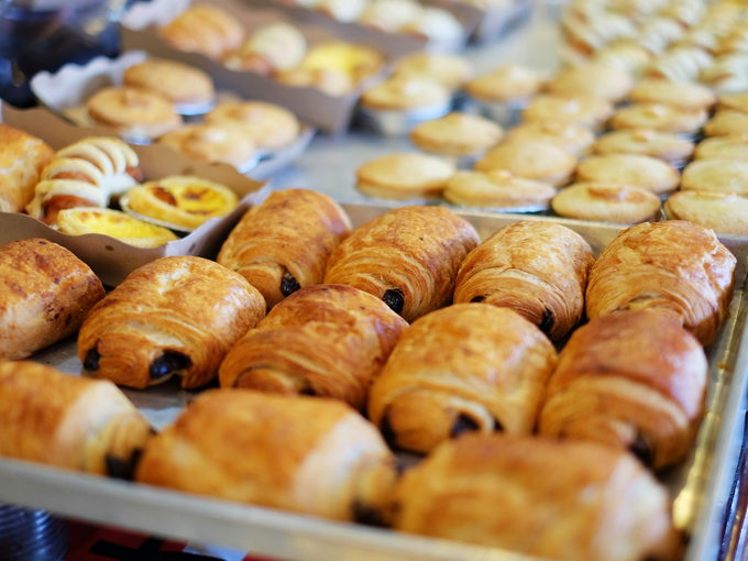 Trays of freshly baked croissants and pastries cooling on a rack.