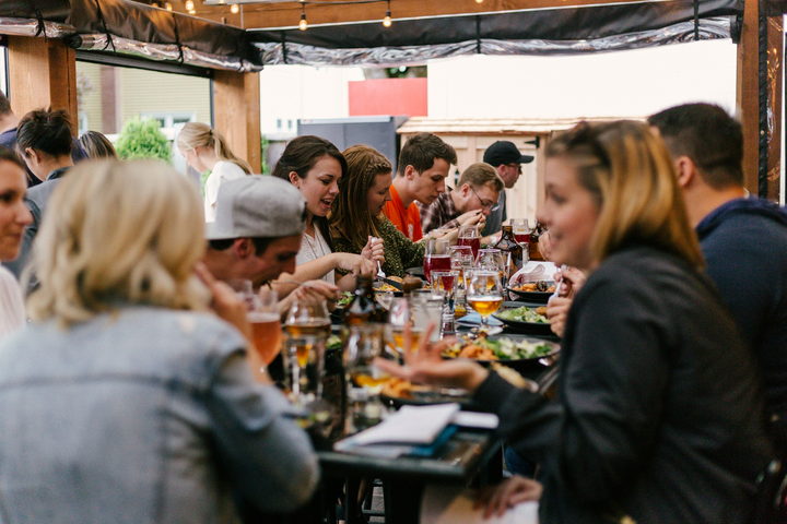 A long table of guests eating and talking in a warmly lit room.